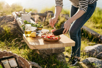 A person is setting an outdoor waterside table for a meal.