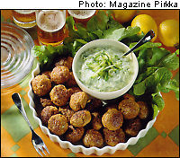 A big pile of meatballs with a dip and herbs on the side.