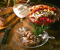 A table set with dark bread, herring, sour cream and a salad.