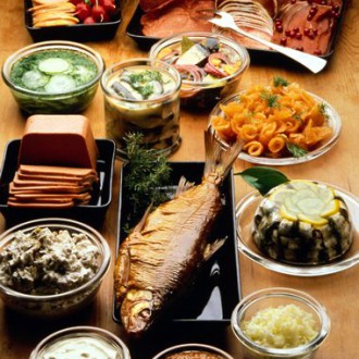 A table filled with different dishes, such as fish, pâté and pickles.