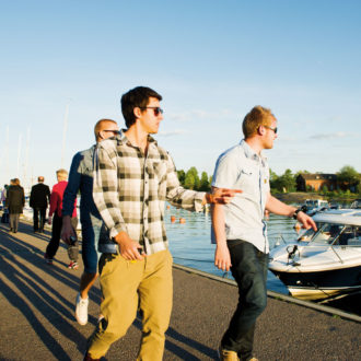 People walking by a river and admiring the boats docked by the banks.