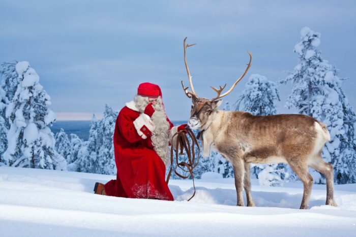 Santa Claus and a reindeer in a snowy landscape.