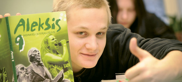 A student giving thumbs-up behind a textbook.