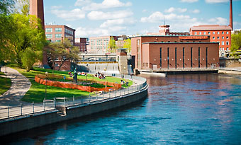 An industrial style brick building and a park by water.