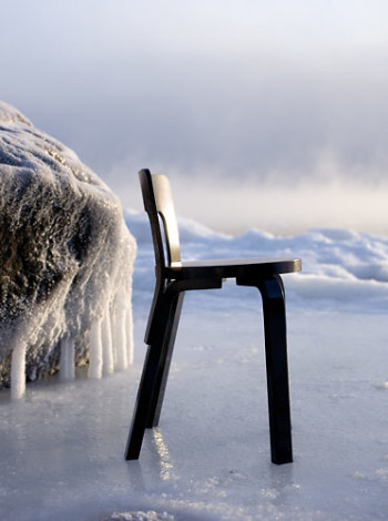 A black chair on ice in a snowy landscape.