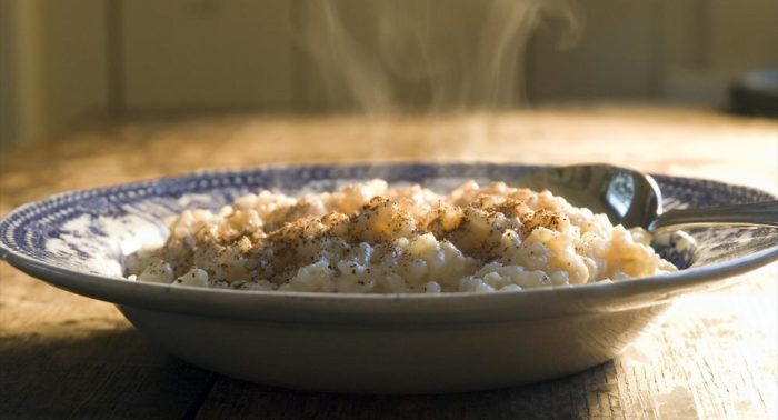 A steaming plate of rice porridge topped with cinnamon.