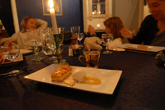 A dessert and a glass of blonde glögi on a table in a dimly lit room.