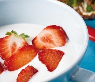 A bowl of milk and strawberries.