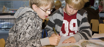 Two schoolboys studying a book.