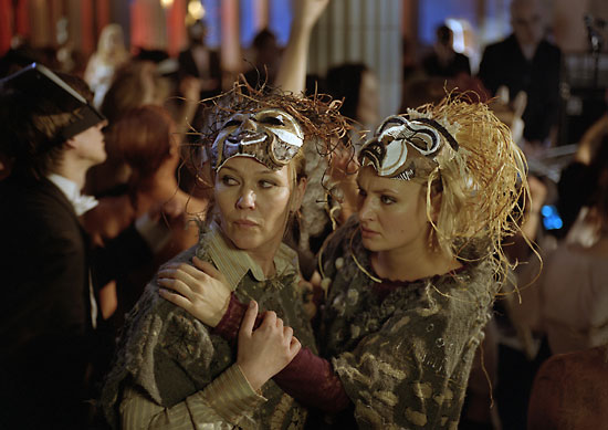 Two women dressed in tribal masks at a masquerade.