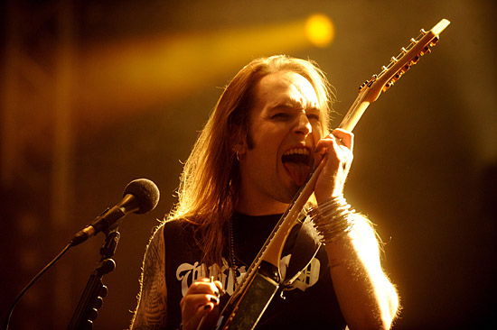 Alexi Laiho pictured licking the neck of his guitar.