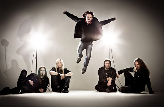 The members of Sonata Arctica posing against a white background; the other members are sitting or lying on the ground whilst frontman Tony Kakko is jumping in the air.