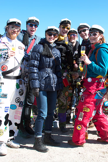 A group of smiling students posing in their student overalls and graduation caps.