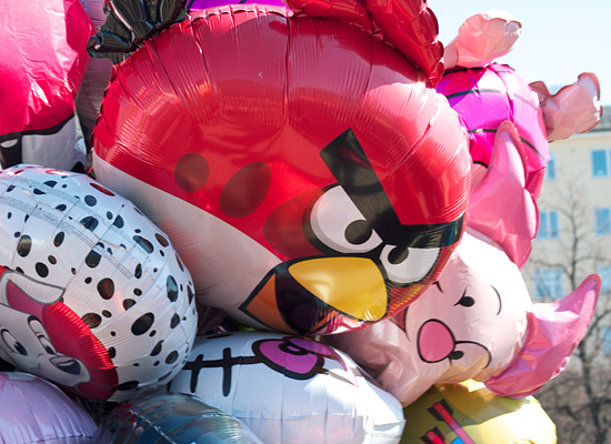 A close-up of a balloon vendor's bundle, showing an Angry Birds and Piglet balloon.