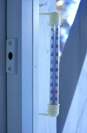 A thermometer outside a window showing a temperature below -20 degrees Celsius.