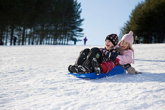 Two enthusiastic-looking children riding a sled.
