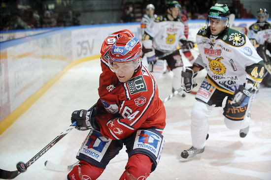 An ice hockey player reaching for the puck.