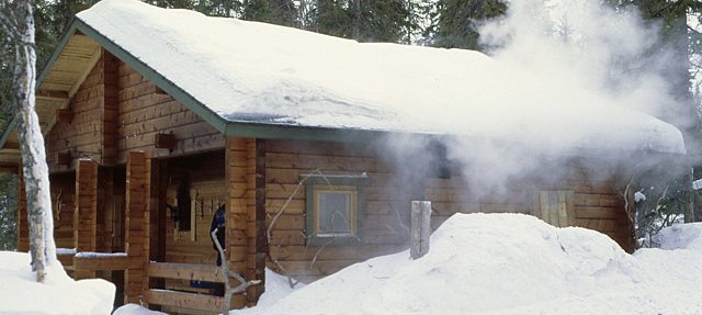 A steaming sauna hut in the snow.