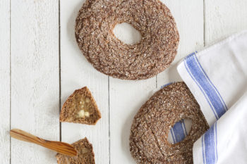 Flat round rye breads on a white wooden surface.