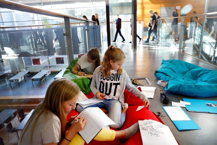 Pupils studying in a corridor on beanbag chairs.