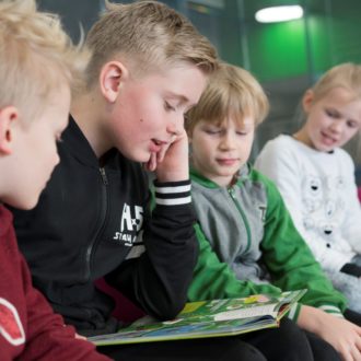 Four pupils reading a book together.