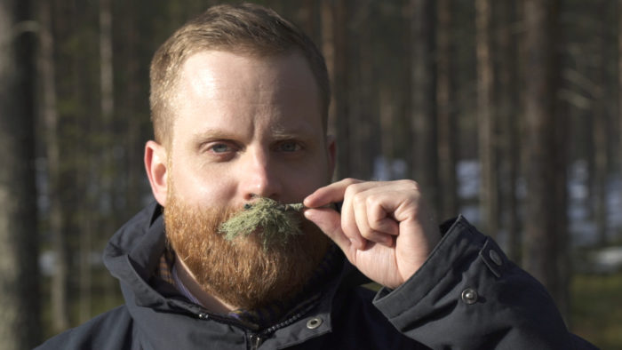 In the middle of a pine forest, Janne Koskimäki shows off a moustache made of moss.
