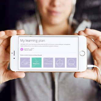 A person holding a phone with two hands, the screen says 'My learning plan'.