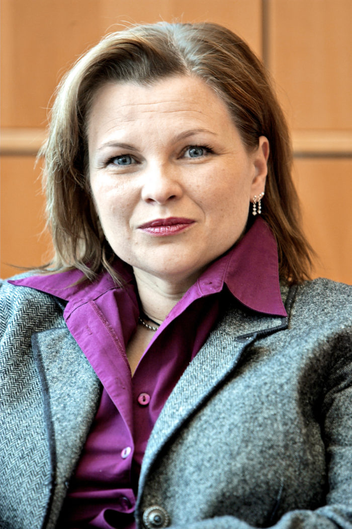 Mari Lättilä pictured in a purple shirt and a grey wool coat.