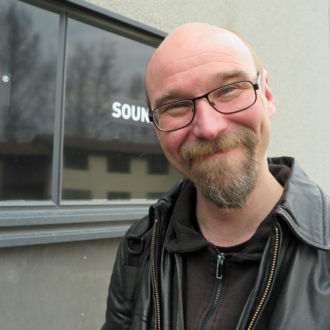 A smiling Esa Lilja posing in front of Sound Inn where musicians can rent space for practice.