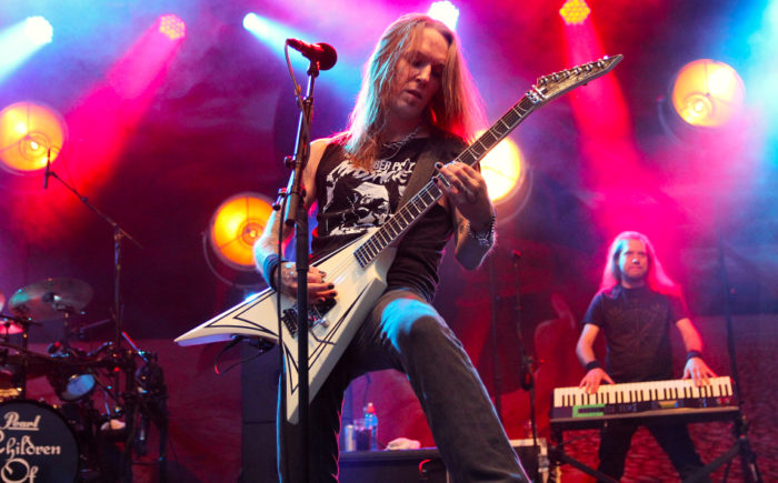 Alexi Laiho playing his guitar on a stage, keyboardist Janne Wirman in the background.