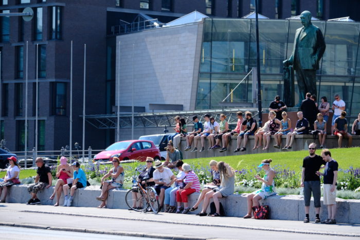 People sitting by a road and a statue.