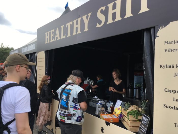 Several concertgoers are ordering food from an outdoor food stand.