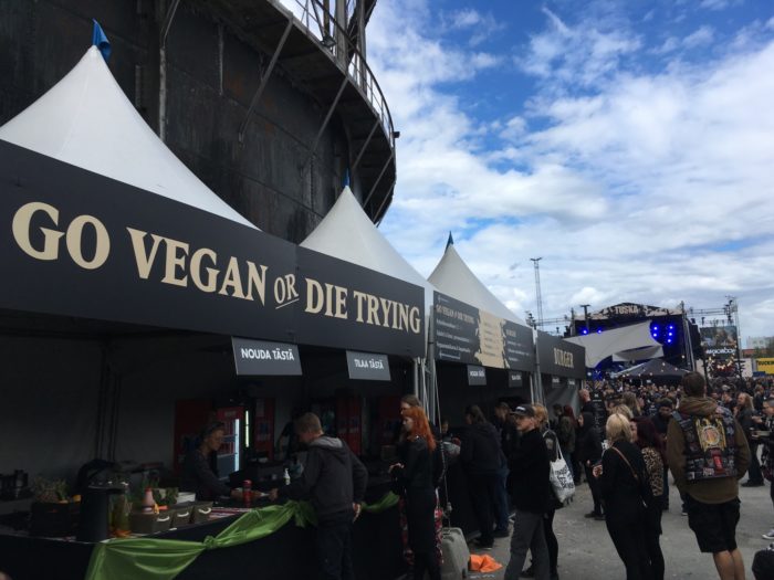 Several concertgoers are ordering food from an outdoor food stand.