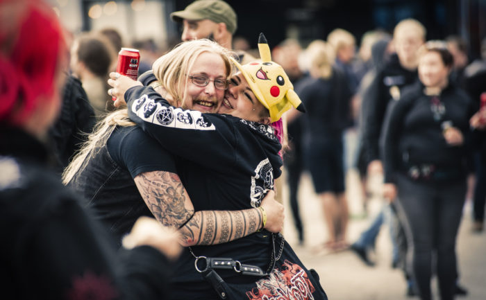 Two concertgoers in black T-shirts hug each other.