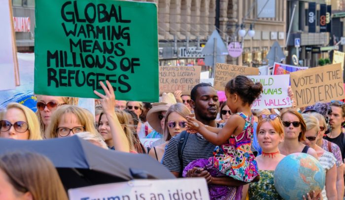 A large crowd of demonstrators, one holding a sign saying 'Global warming means millions of refugees'.
