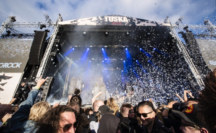 A crowd watches a concert on a large outdoor stage.