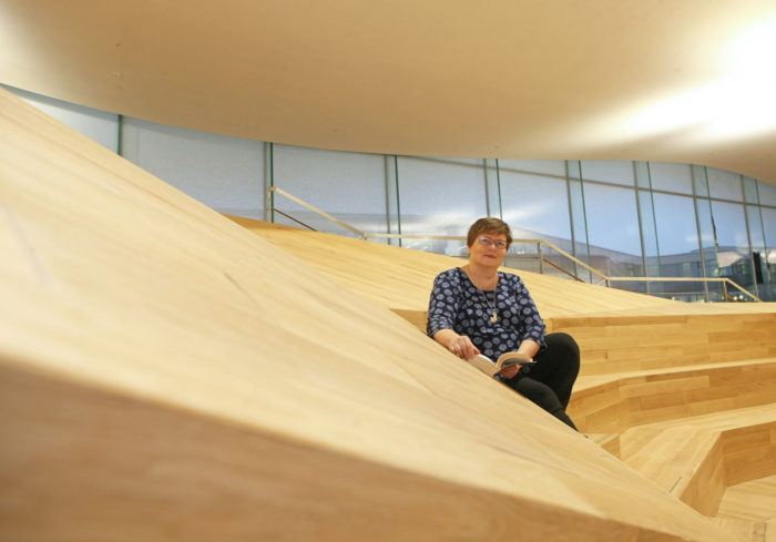كاتري فانتينين، مديرة خدمات مكتبة مدينة هلسنكي، تجلس بصحبة كتاب في أحد طرفي الطابق الثالث في مكتبة Oodi.