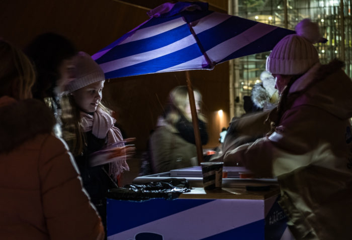 An ice cream vendor offering samples to passers-by.