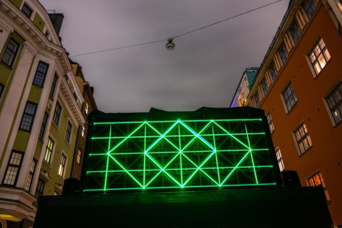 Geometric shapes in green light installed between two buildings.