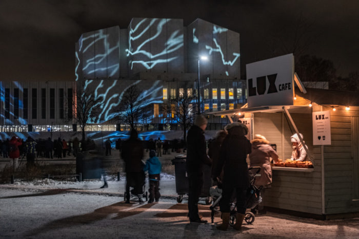 People standing by a small café shed with Finlandia hall in the background.