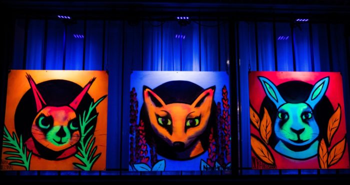 Graffiti showing a squirrel, a fox and a rabbit lit with ultraviolet light.
