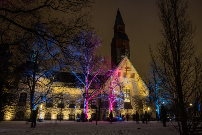 Trees illuminated with pink and blue lights, National Museum in the background.