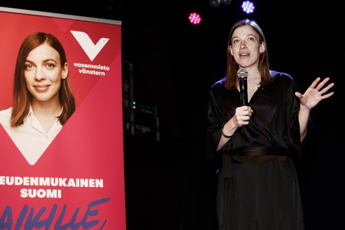 Li Andersson giving a speech next to her campaign roll-up. 