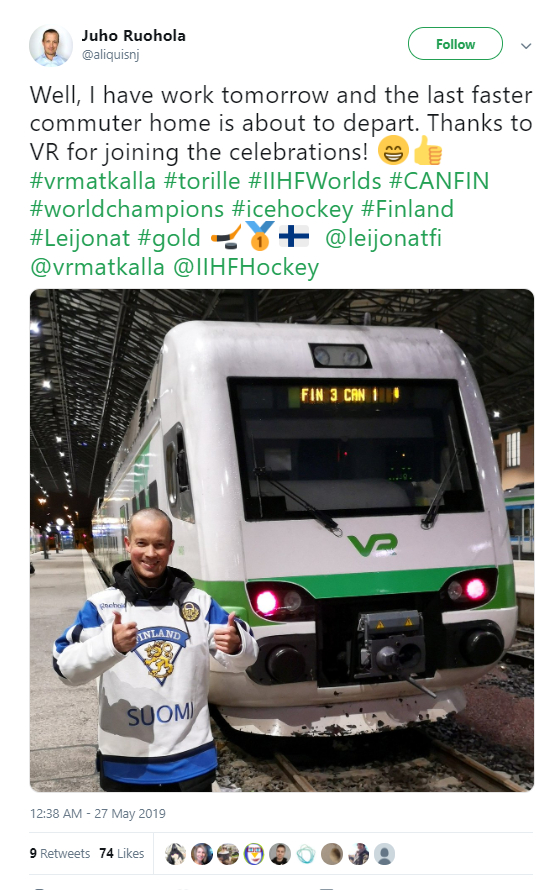A man dressed in Finland's national ice hockey jersey next to a train.