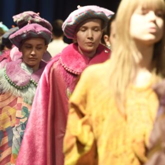 Colourfully clad models lined up on a catwalk.