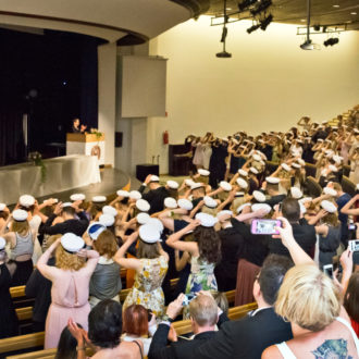 An auditorium filled with students putting their graduation caps on.
