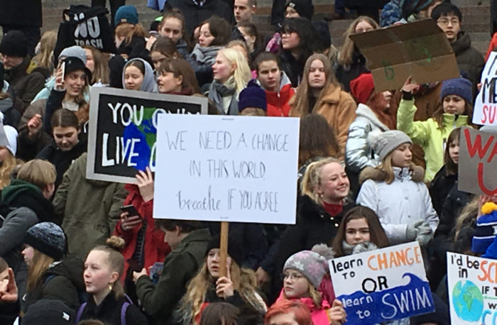 A large crowd of young people hold signs at a climate demonstration.
