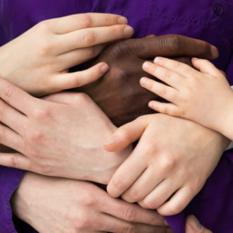 Multiple hands and arms of different-aged people hold on to each other.