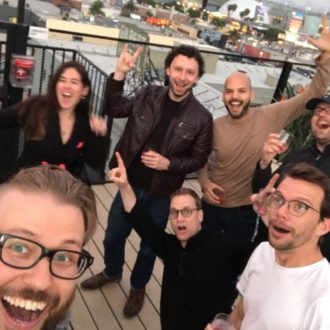 A group of happy-looking people is gathered on a rooftop patio.