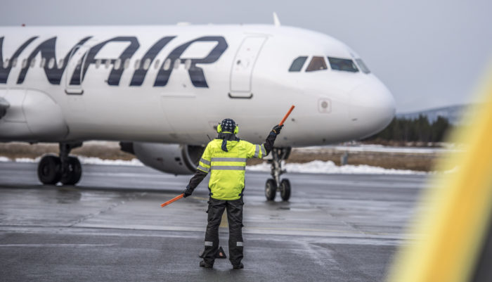 A ground service worker guides a plane to its parking space.